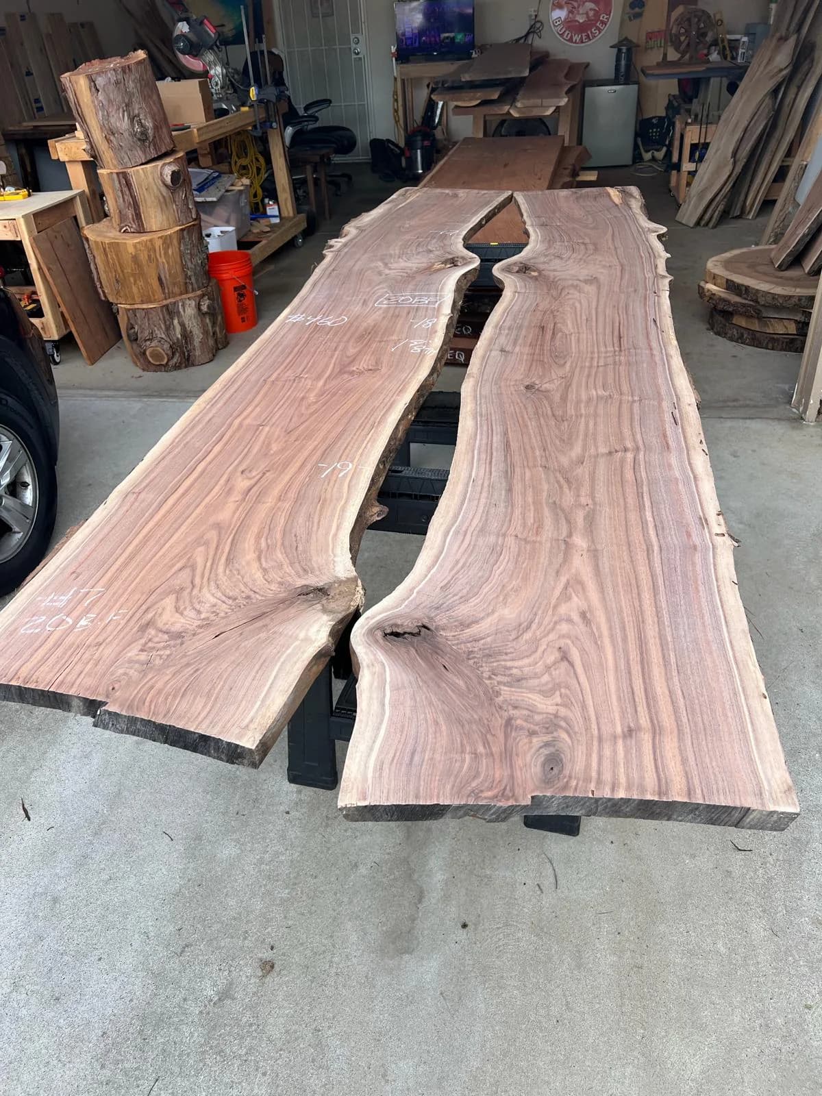 Two live-edge Oklahoma Black Walnut slabs showing natural grain, knots, and irregular edges in the workshop